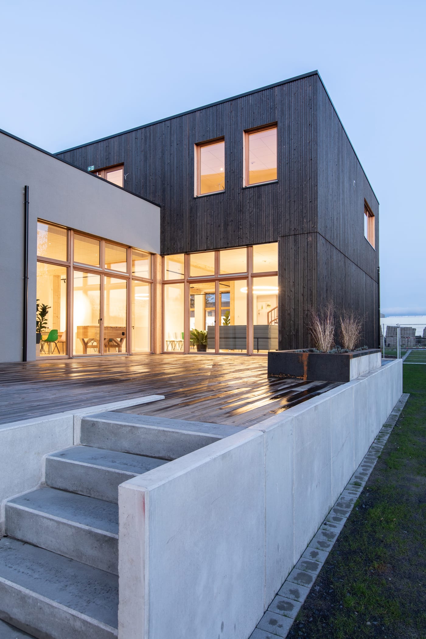 Illuminated wood-framed windows on a modern home at dusk