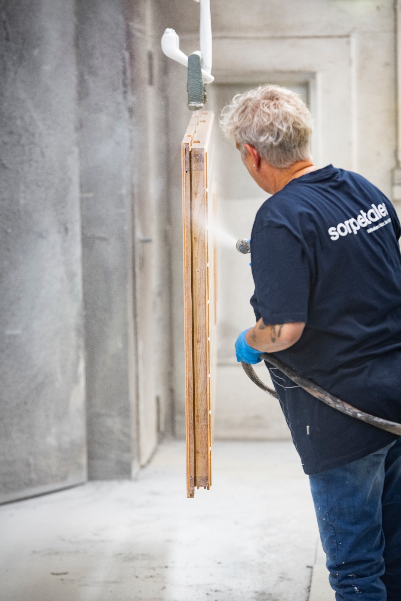 Sorpetaler craftsperson spray-finishing a wood door panel