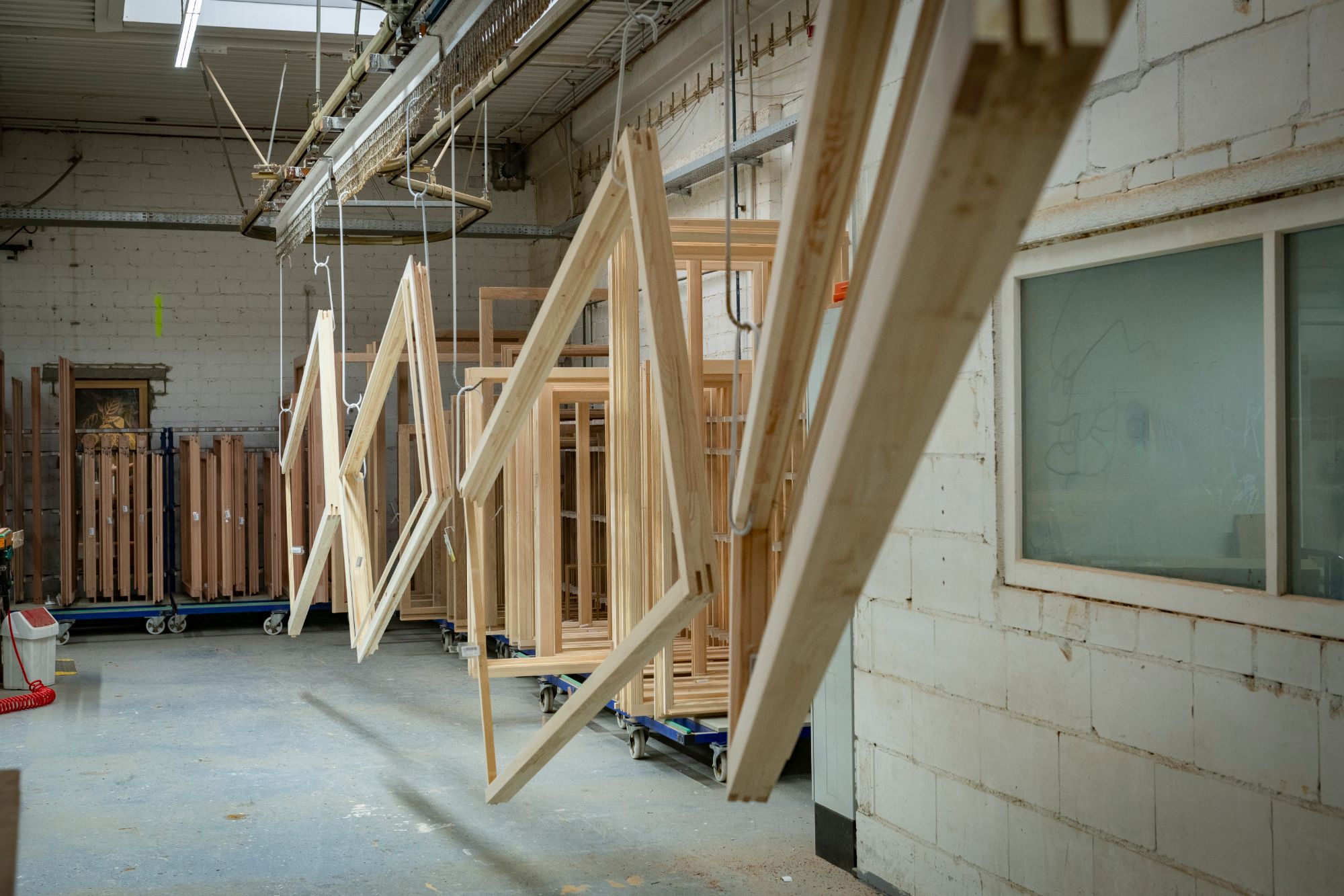 Wood window and door frames hanging on the overhead finishing line